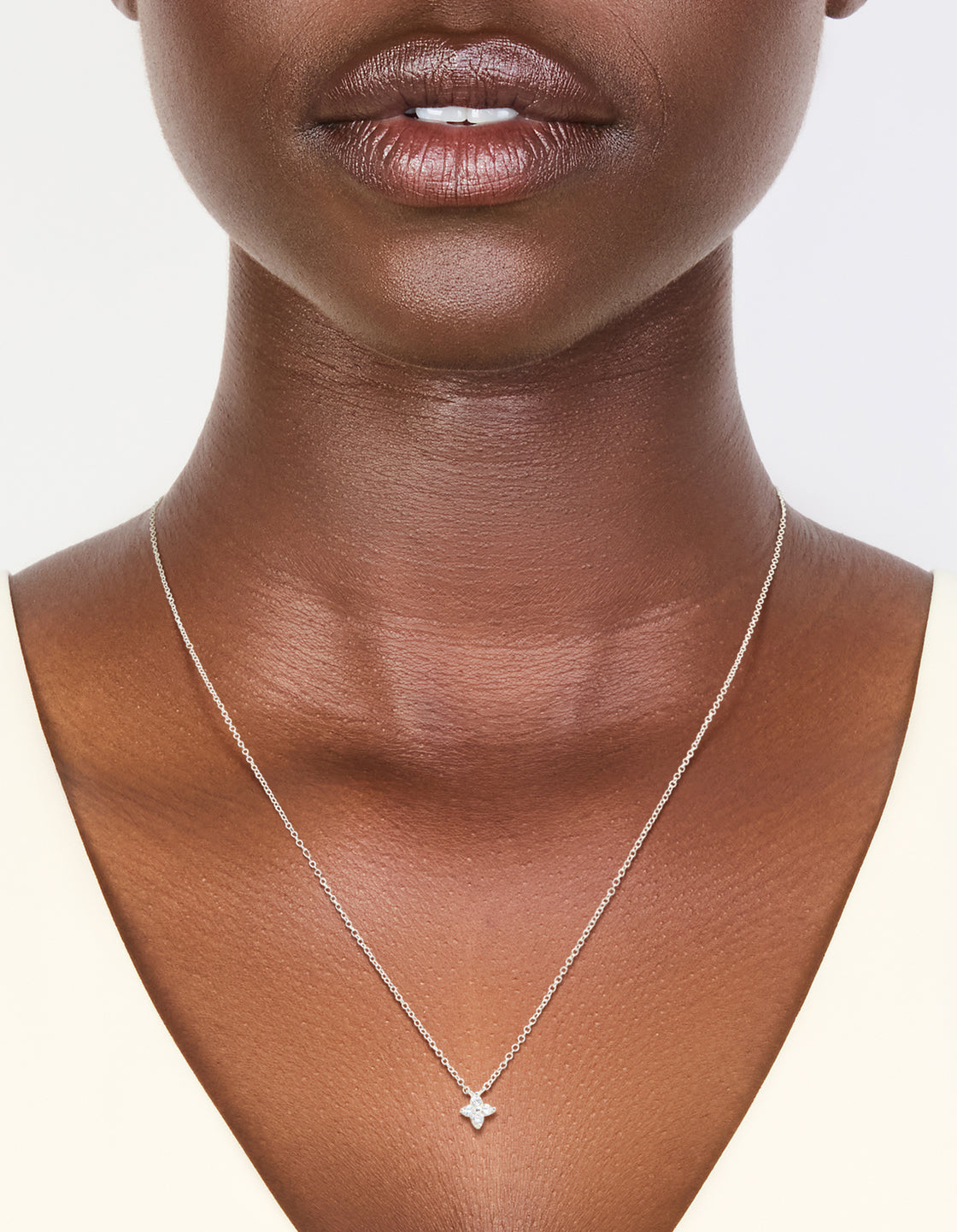 Featuring a sterling silver cubic zirconia micro flower pendant in dainty on neck view