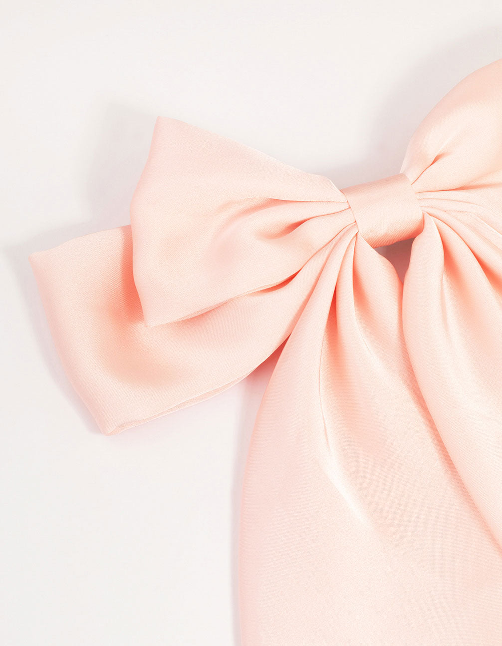 Showcasing a pink satin fabric bow barrette clip with solid print detail view