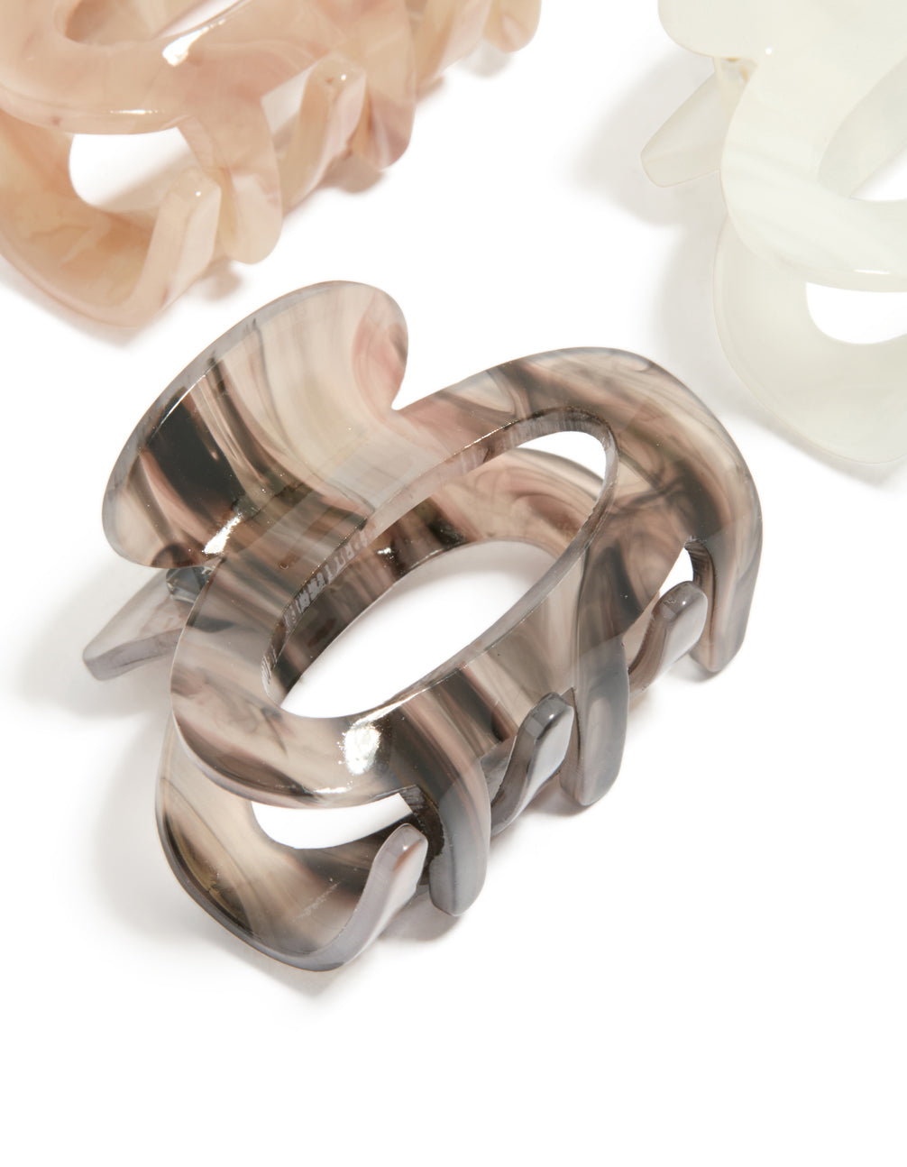 Showcasing oval acrylic mini claw clips in a 3-pack with tan, ivory, and rosy brown hues detail view