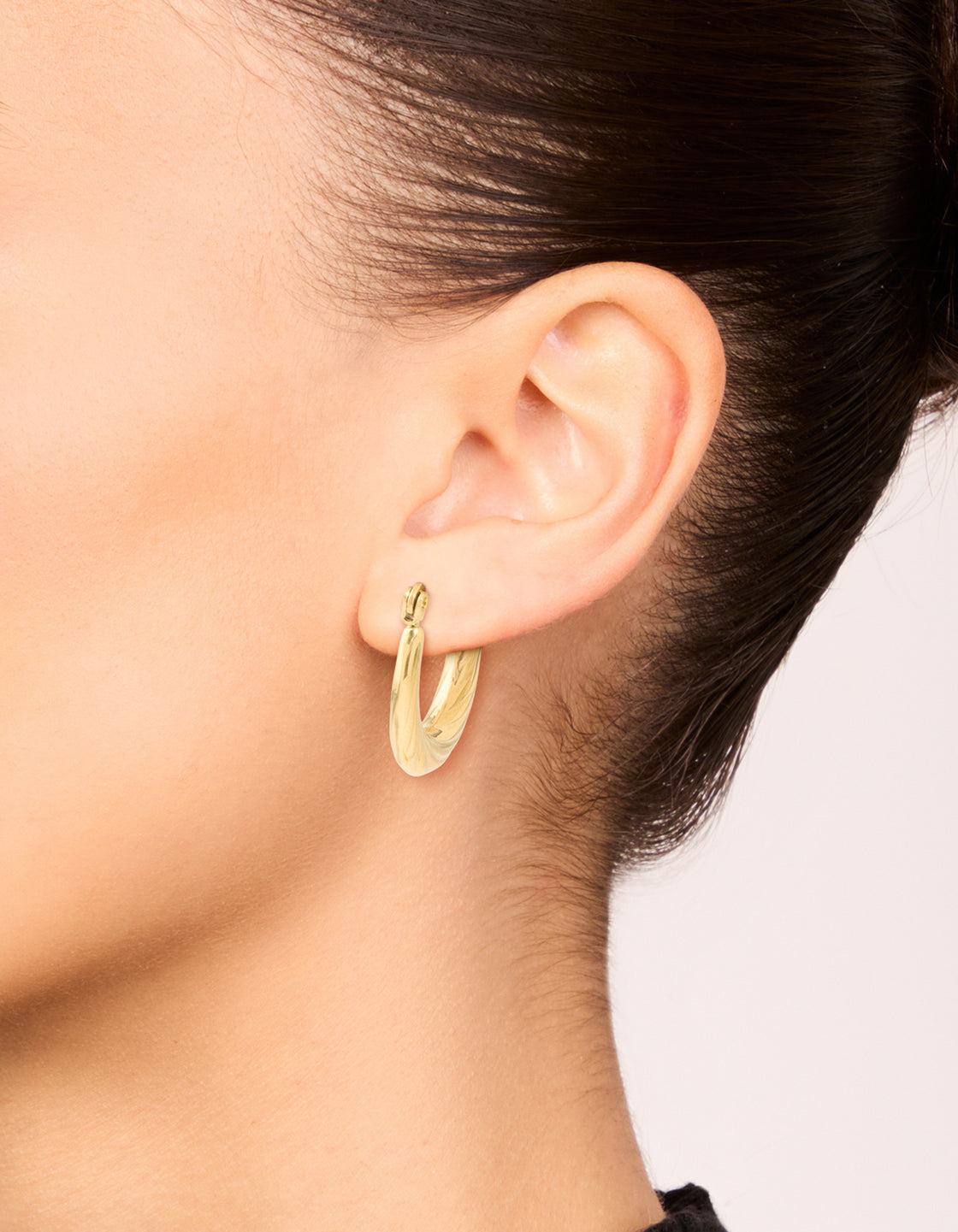 Featuring waterproof twisted hoop earrings in gold plated stainless steel on ear view