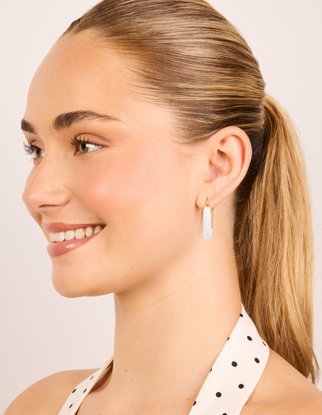 Designed with waterproof gold plated stainless steel long hoop earrings featuring white enamel on model view