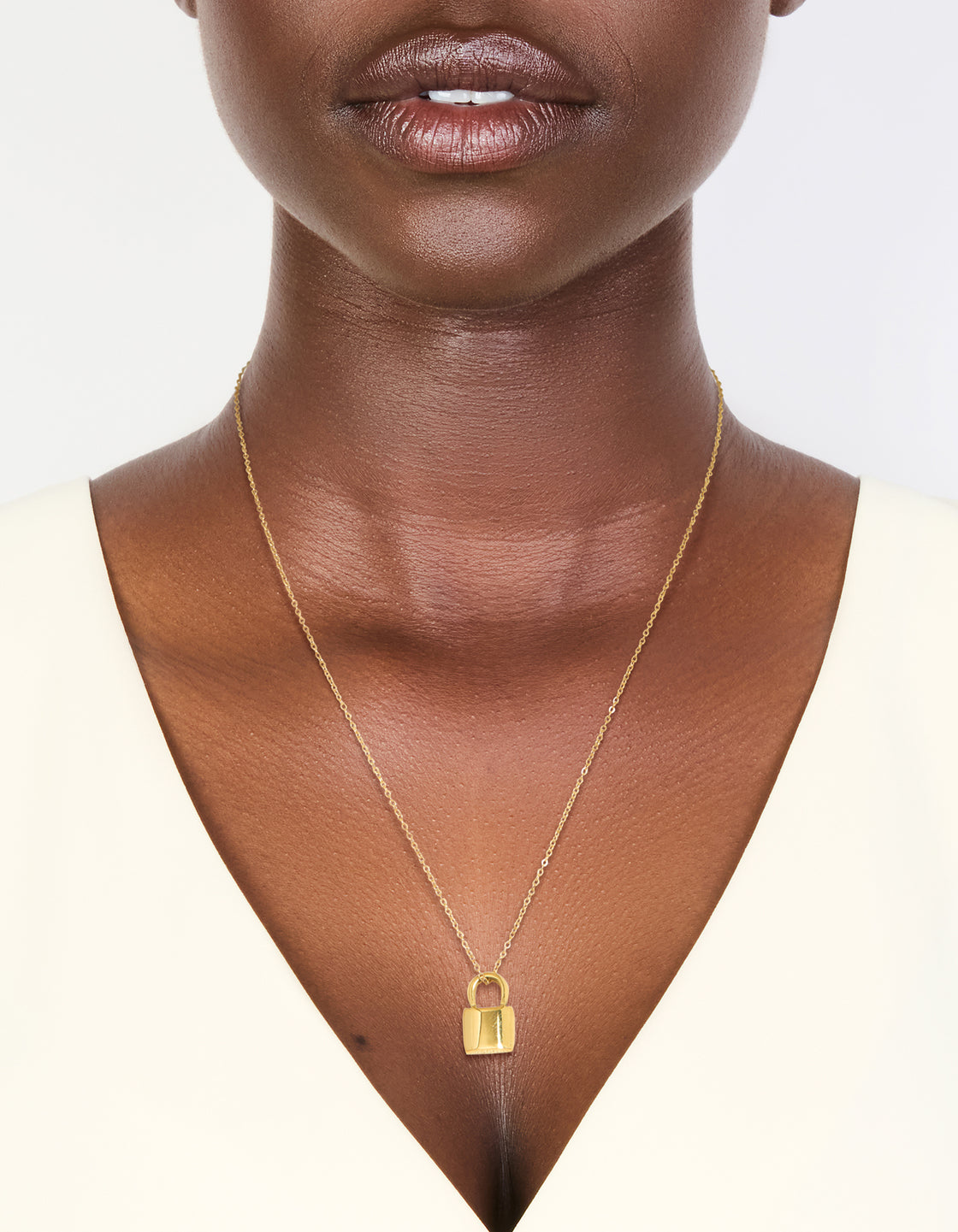 Showcasing a waterproof gold plated stainless steel lock pendant necklace featuring dainty styling in gold on neck view