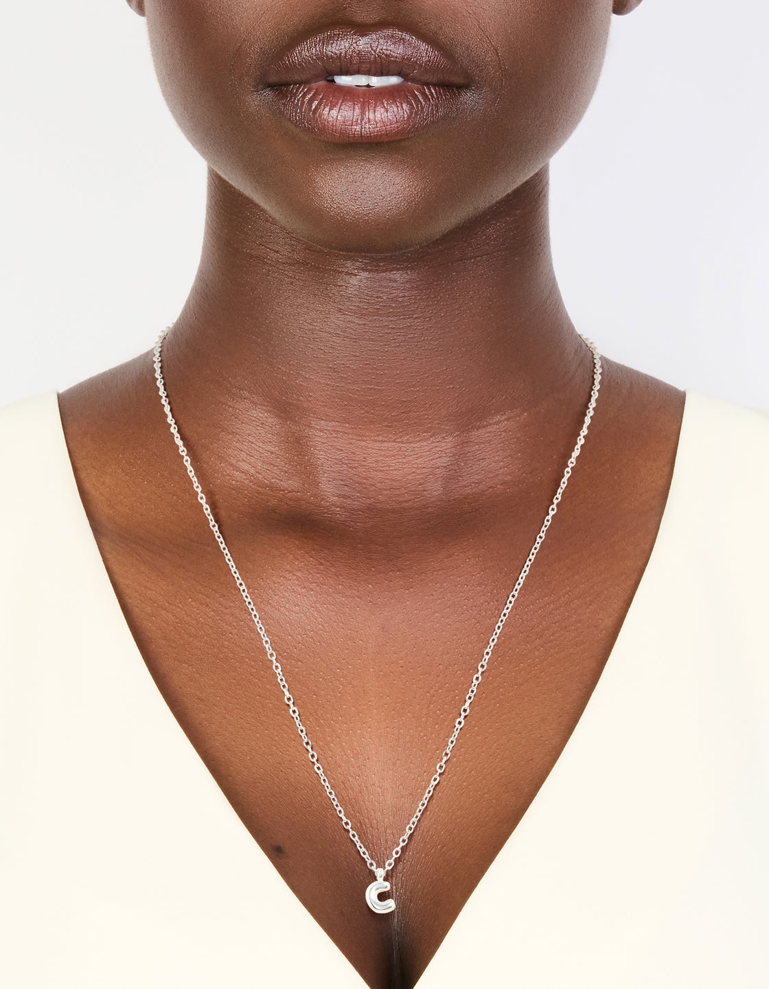 Showcasing a waterproof stainless steel mini bubble letter C necklace with initial pendant in silver on neck view