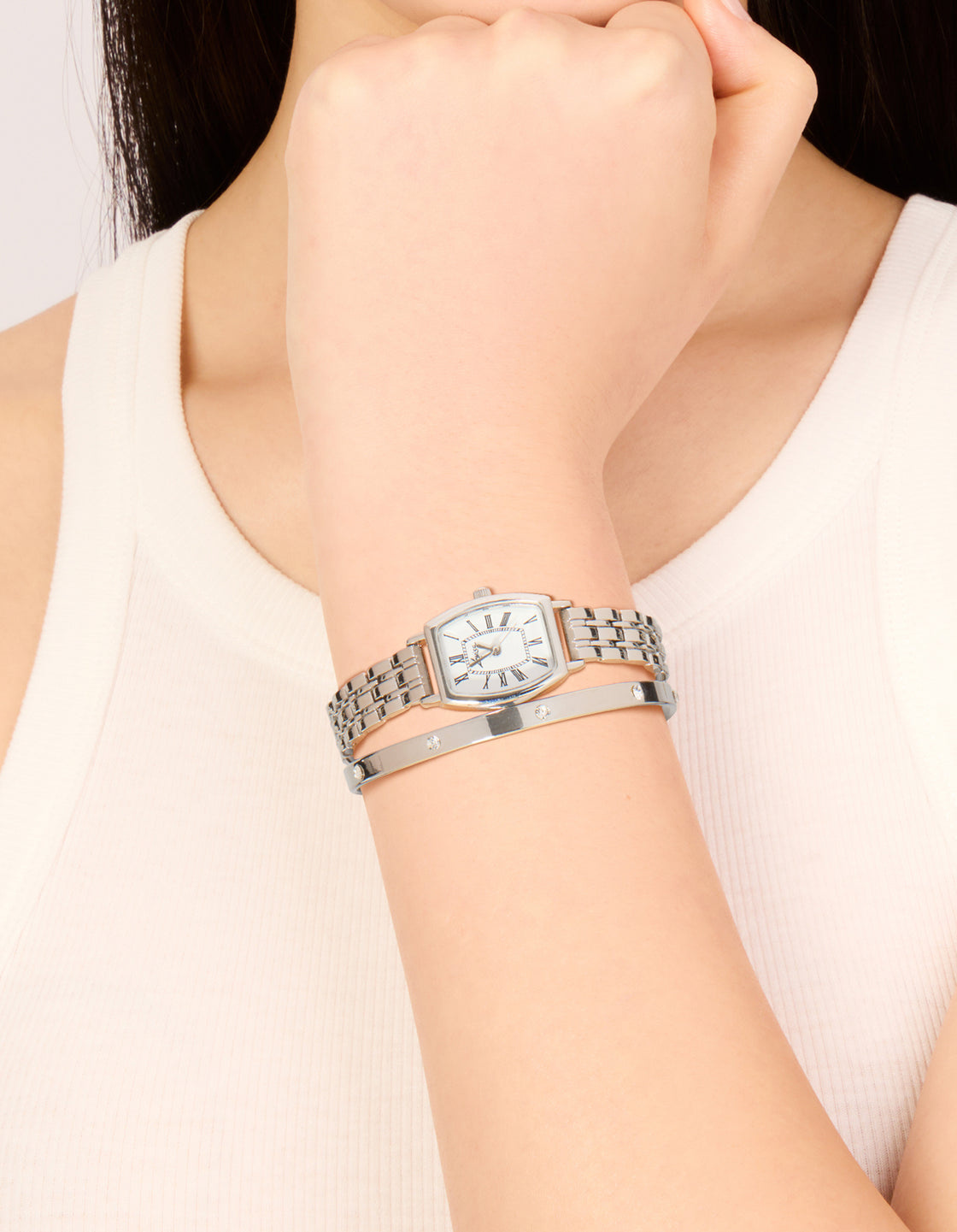 Showcasing a women's casual analog watch and wrist cuff set with white dial featuring roman numerals, rectangle shape, link band in silver on wrist view