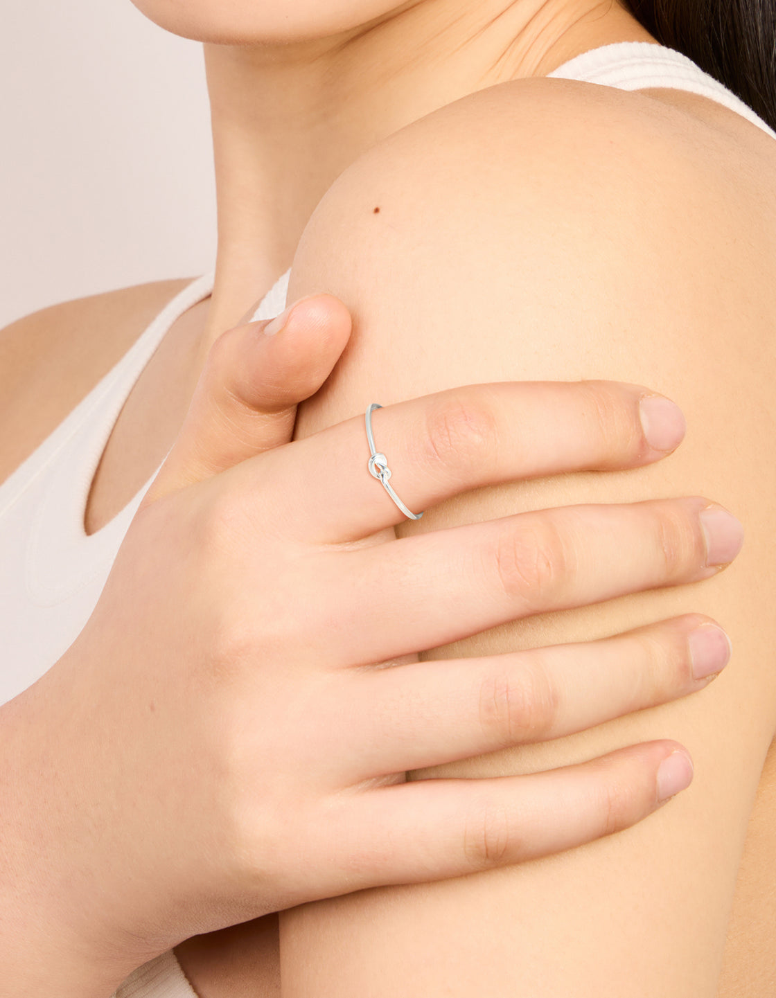 Showcasing a dainty sterling silver tiny knot ring on finger view
