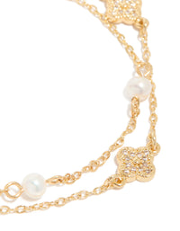Designed with floral details, this dainty gold plated cubic zirconia and freshwater pearl layered bracelet shown in close up view - link has visual effect only