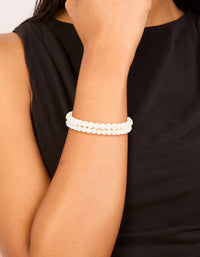 Showcasing Gold Plated Classic Pearl Bracelets 2-Pack accents in white and gold on wrist view - link has visual effect only