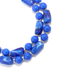 Showcasing a dark blue acrylic beaded long layered necklace with balls and statement style in royal and dodger blue with gold accents close up view - link has visual effect only