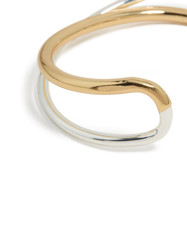 Highlighting a mixed metal open crossover wrist cuff with gold plated and silver finish in bangle form close up view