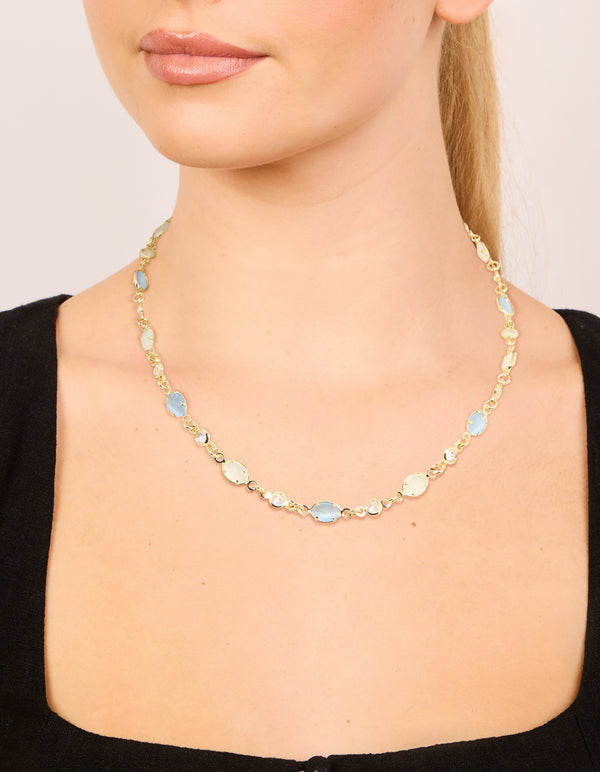 Showcasing a gold plated blue and white oval cubic zirconia necklace in dainty styling on neck view