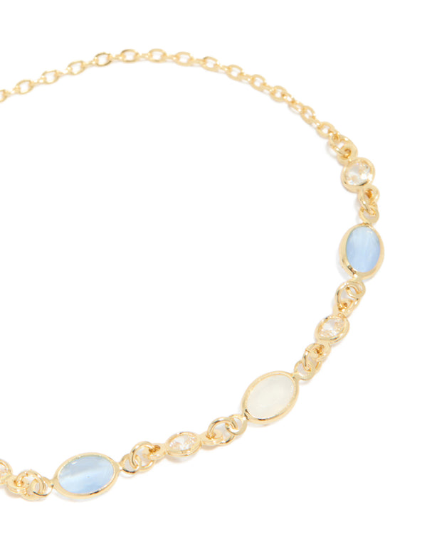 Highlighting the intricate details of a gold plated blue and beige oval cubic zirconia toggle bracelet in close up view