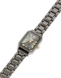 Featuring a black coated metal rectangle roman numeral watch with gold numerals, analog display, link band, and formal styling watch face detail view - link has visual effect only