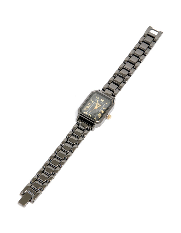 Showcasing a black coated metal rectangle roman numeral watch with gold numerals, analog display, link band, and formal styling front view