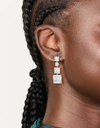 Showcasing silver cubic zirconia square drop earrings worn on ear view - link has visual effect only