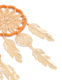 Detailed perspective of statement dreamcatcher earrings highlighting gold feathers with orange yarn and charm post detail view - link has visual effect only