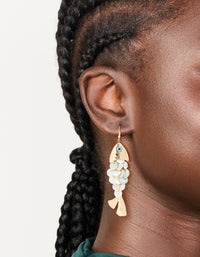 Showcasing gold evil eye fish drop earrings with animal and ocean inspired charm in a statement style on ear view - link has visual effect only
