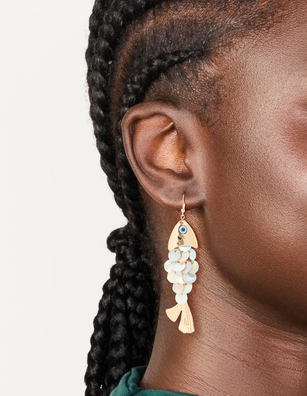 Showcasing gold evil eye fish drop earrings with animal and ocean inspired charm in a statement style on ear view