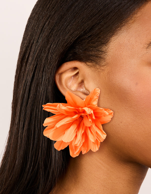 Showcasing statement orange paper flower petal earrings on ear view