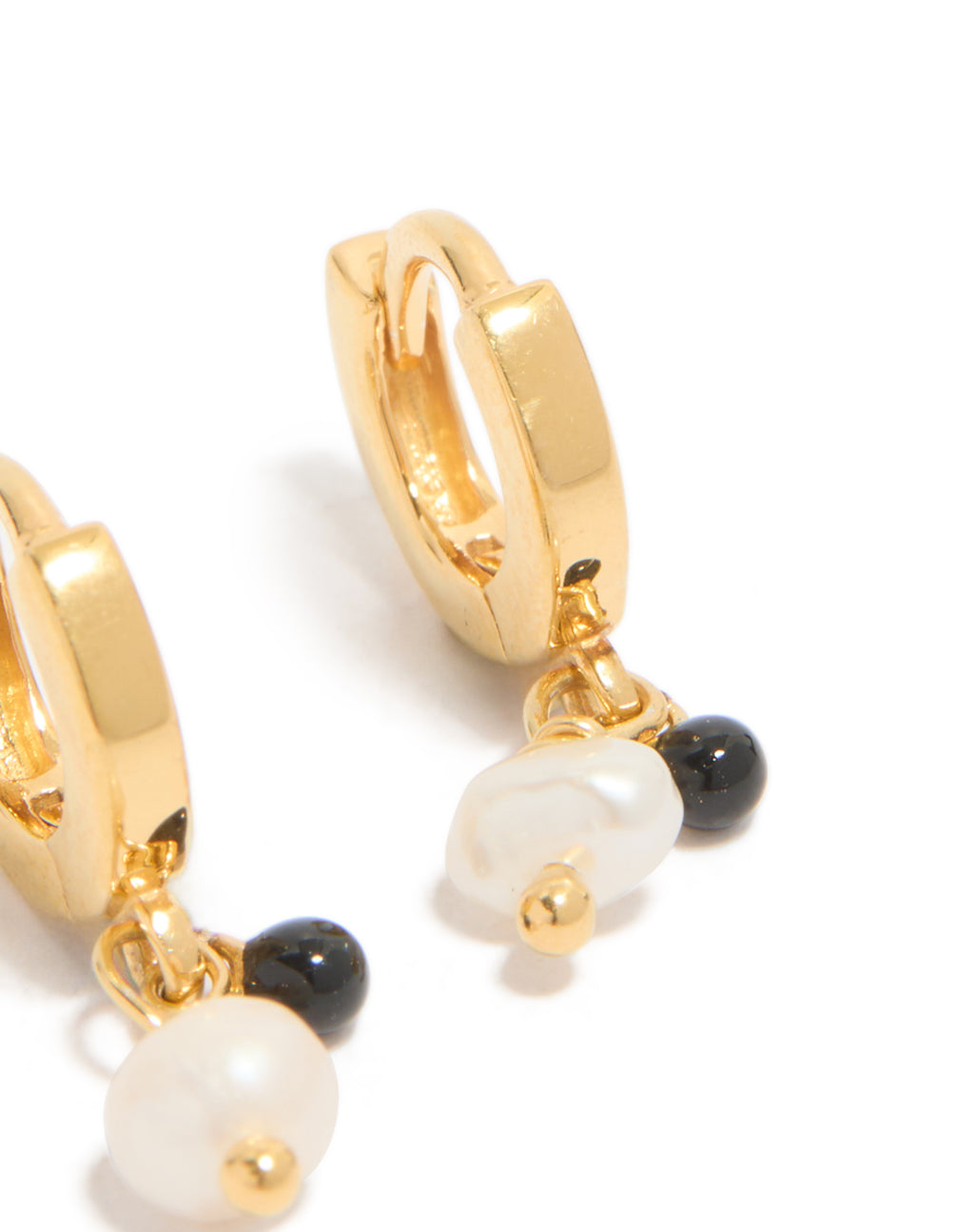 Displaying gold plated sterling silver and pearl drop huggie earrings in ivory and black close up view