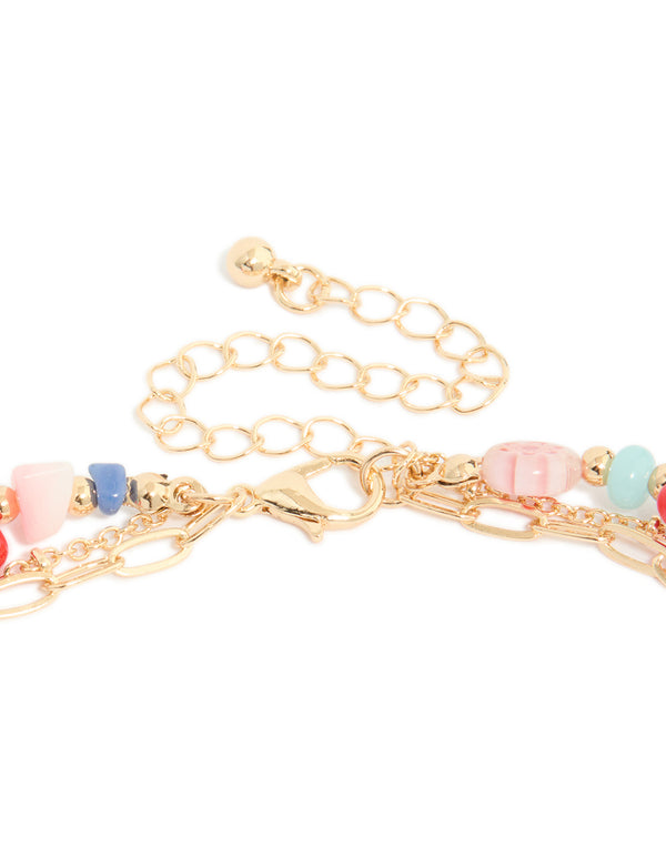 Highlighting a gold fish pendant and multicoloured beaded layered necklace with floral and ocean features in statement design clasp detail view