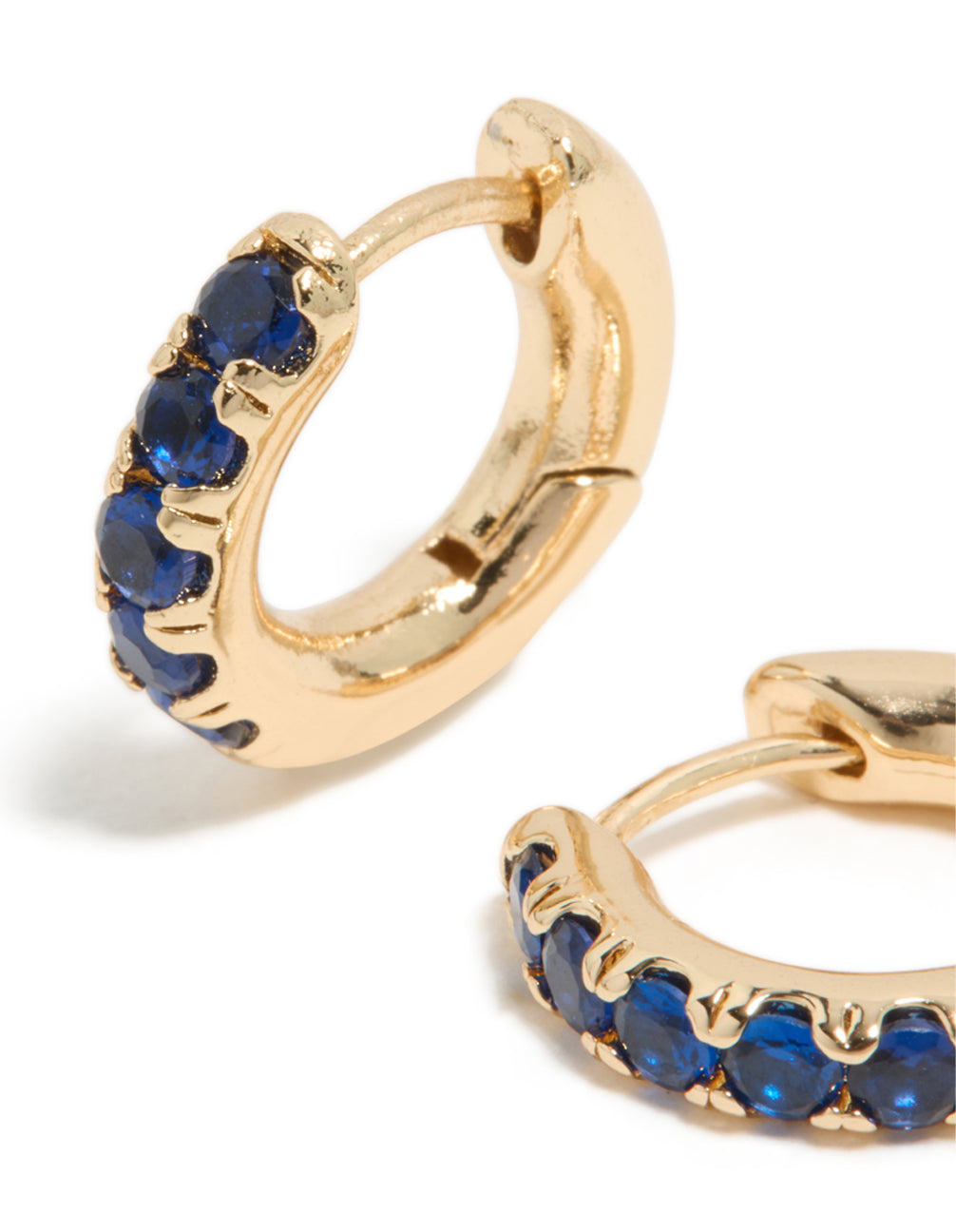 Crafted from cubic zirconia, these small gold and dark blue huggie clicker earrings showcase fine detailing in a close up view