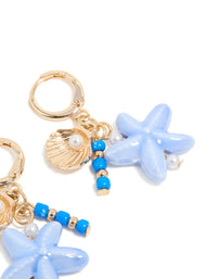 Crafted from gold, these sea life charm huggie earrings feature ocean-inspired shell, beaded accents, pearls, and starfish accents in a post detail view - link has visual effect only