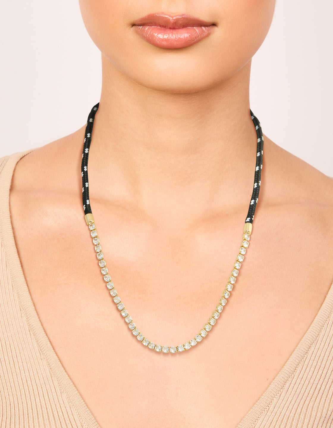 Highlighting a waterproof tennis necklace in gold plated stainless steel with black cord, featuring statement design on neck view