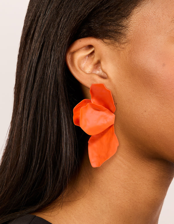 Showcasing orange coated metal flower petal drop earrings with floral design on ear view