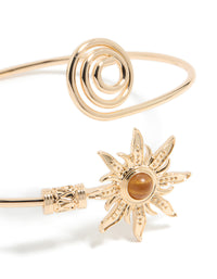 Crafted with celestial sun detailing and a swirl design, this gold statement cuff is shown in close up view - link has visual effect only