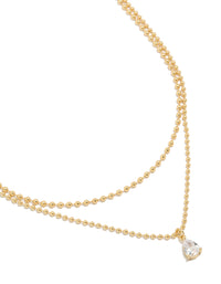 Showcasing a gold plated cubic zirconia teardrop pendant and ball layered necklace featuring crystal in dainty style close up view - link has visual effect only