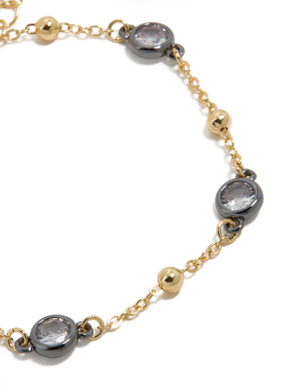 Bracelet featuring mixed metal, cubic zirconia stones set in grey bezels alternating with gold plated balls on delicate chain close up view
