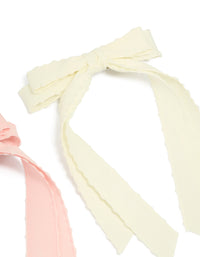 Crafted with scalloped edges, this 2-pack of fabric bow clips in solid light pink and ivory side view - link has visual effect only