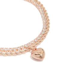 Highlighting a rose gold plated cubic zirconia tennis and heart layered bracelet with charm detail close up view - link has visual effect only