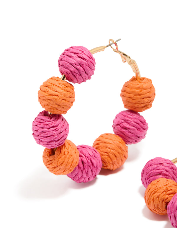 Beautifully crafted statement hoop earrings featuring paper balls in hot pink, coral and gold close up view