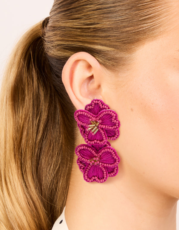 Showcasing hot pink fabric beaded double flower drop earrings with statement design and gold accents on ear view