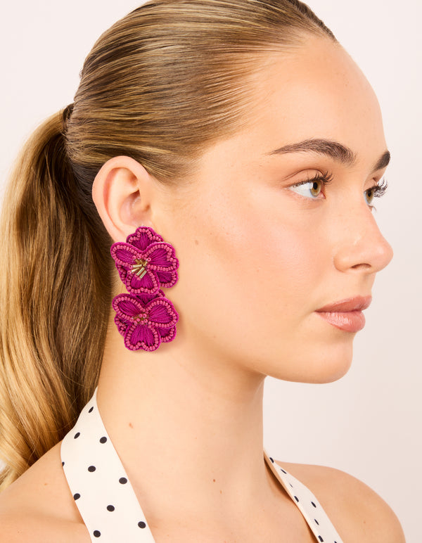 Crafted from hot pink fabric with beaded double flower drop earrings featuring statement design and gold accents on model view