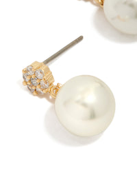 Detailed view of gold plated small round cubic zirconia and pearl drop earrings in white highlighting craftsmanship close up view - link has visual effect only