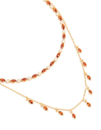 Showcasing a gold plated red cubic zirconia tennis and teardrop charm layer necklace with statement styling close up view - link has visual effect only