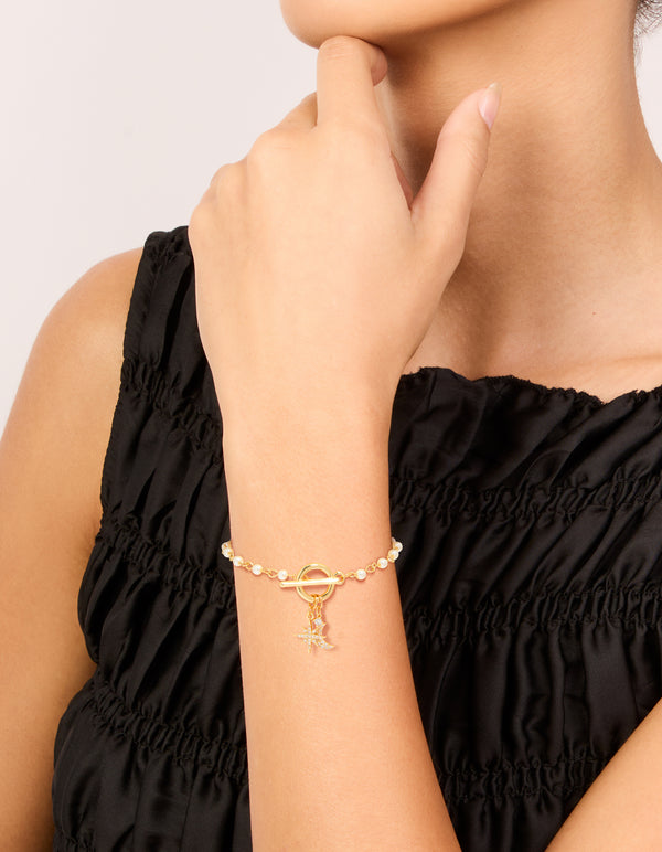 Elegant gold plated pearl and cubic zirconia bracelet with celestial star and moon charm worn on wrist view