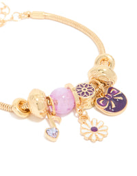This gold bow and music note charm bracelet showcases beads, floral elements, and heart details in purple, pink, and white close up view - link has visual effect only