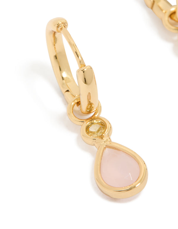 Elegant gold plated huggie earrings featuring pink cubic zirconia teardrop and statement design close up view