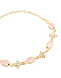 Featuring a gold plated bracelet with floral cubic zirconia and oval pink stones in a close up view - link has visual effect only