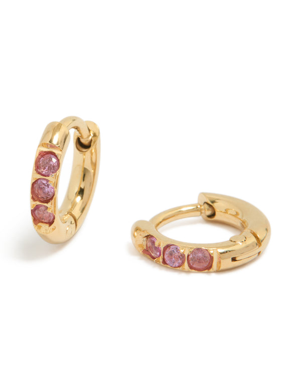 Featuring waterproof gold plated stainless steel huggie earrings with pink cubic zirconia stones front view