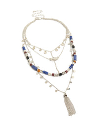 Crafted with cubic zirconia and crystal, this blue and brown beaded layered necklace features a coin and tassel charm disc, finished in silver and shown in a front view - link has visual effect only
