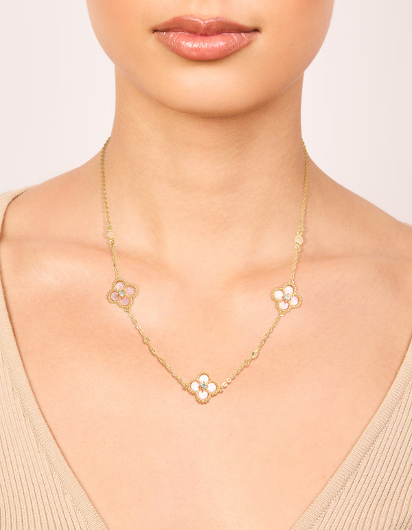 Showcasing a gold plated pink cubic zirconia flower trio necklace with floral in statement style on neck view