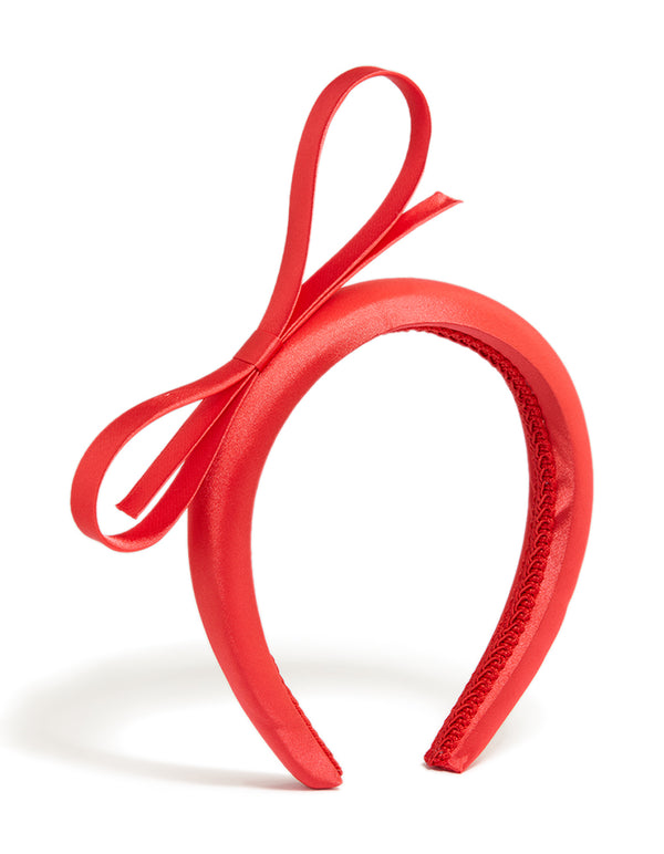 Showcasing a red satin bow headband in solid design side view