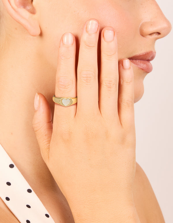 Displaying a gold plated stainless steel dainty heart signet ring with waterproof material on finger view