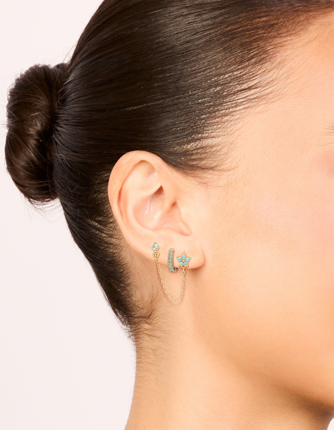 Featuring gold light blue cubic zirconia chain flower and huggie earrings pack on ear view