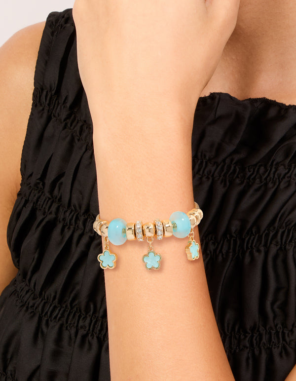 Featuring a beaded charm bracelet with floral details in gold and light blue on wrist view