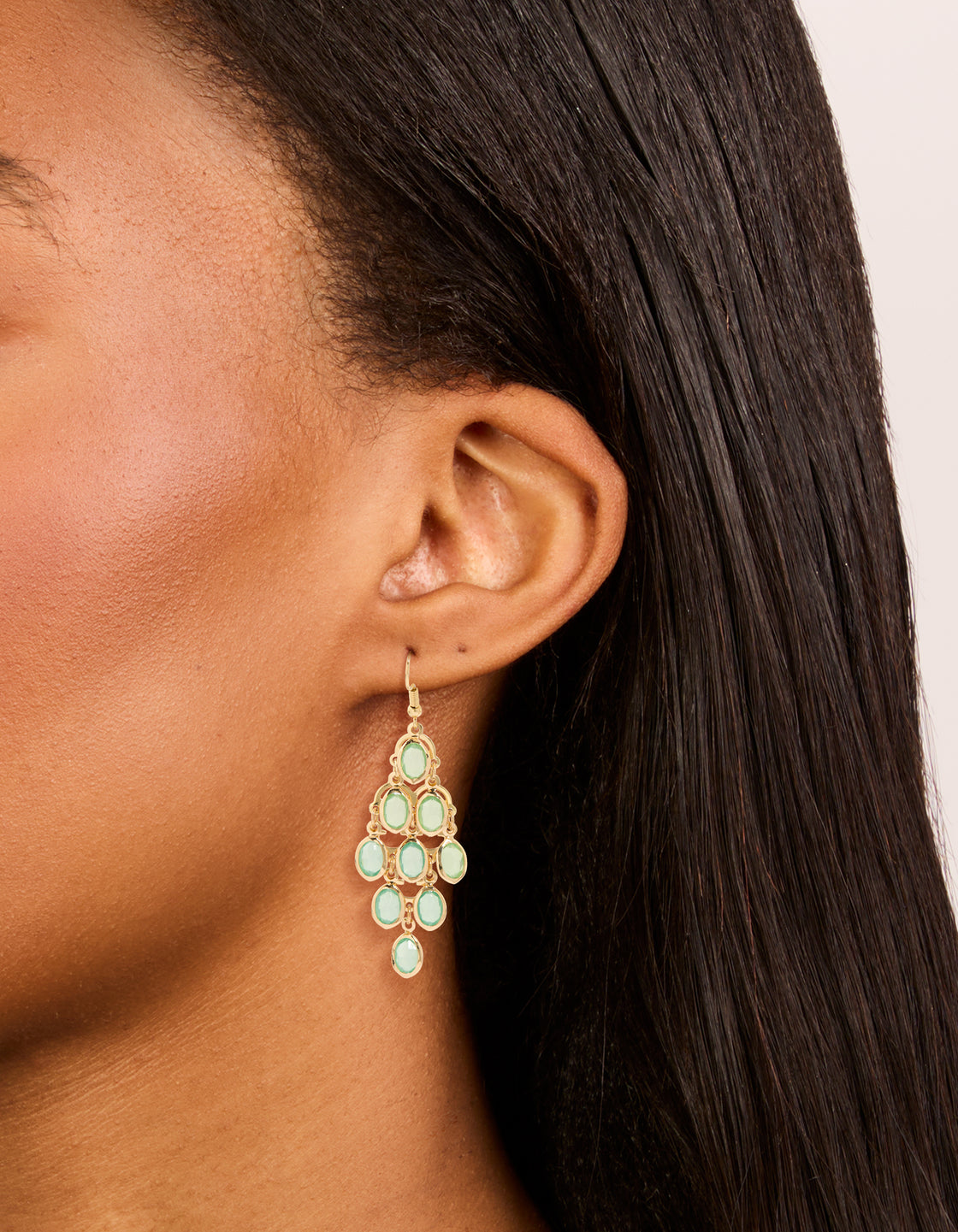 Elegant statement style gold green diamantes cascading drop earrings featuring pale green stones on ear view